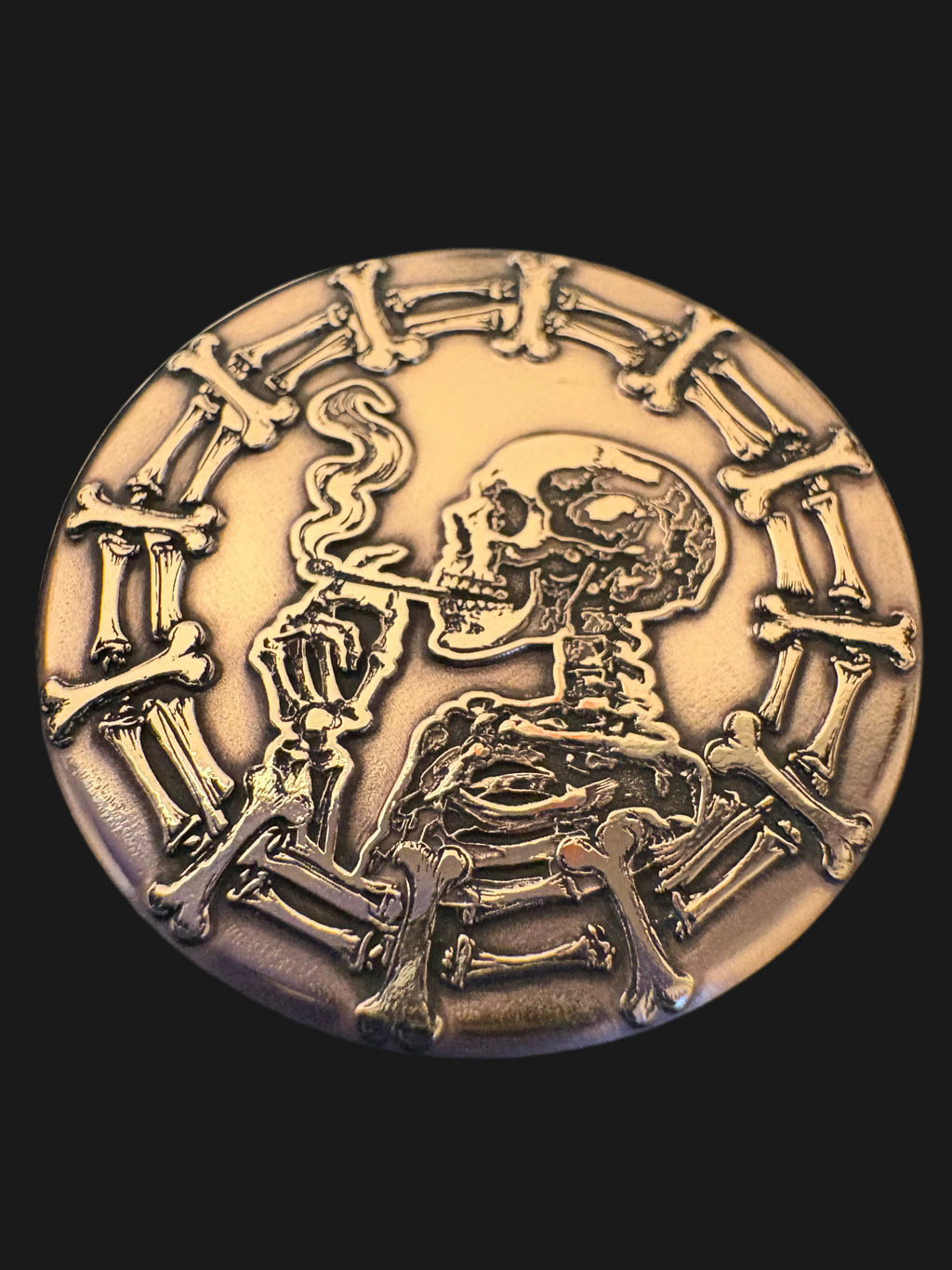 Bronze-colored coin with a skeleton design on a black background