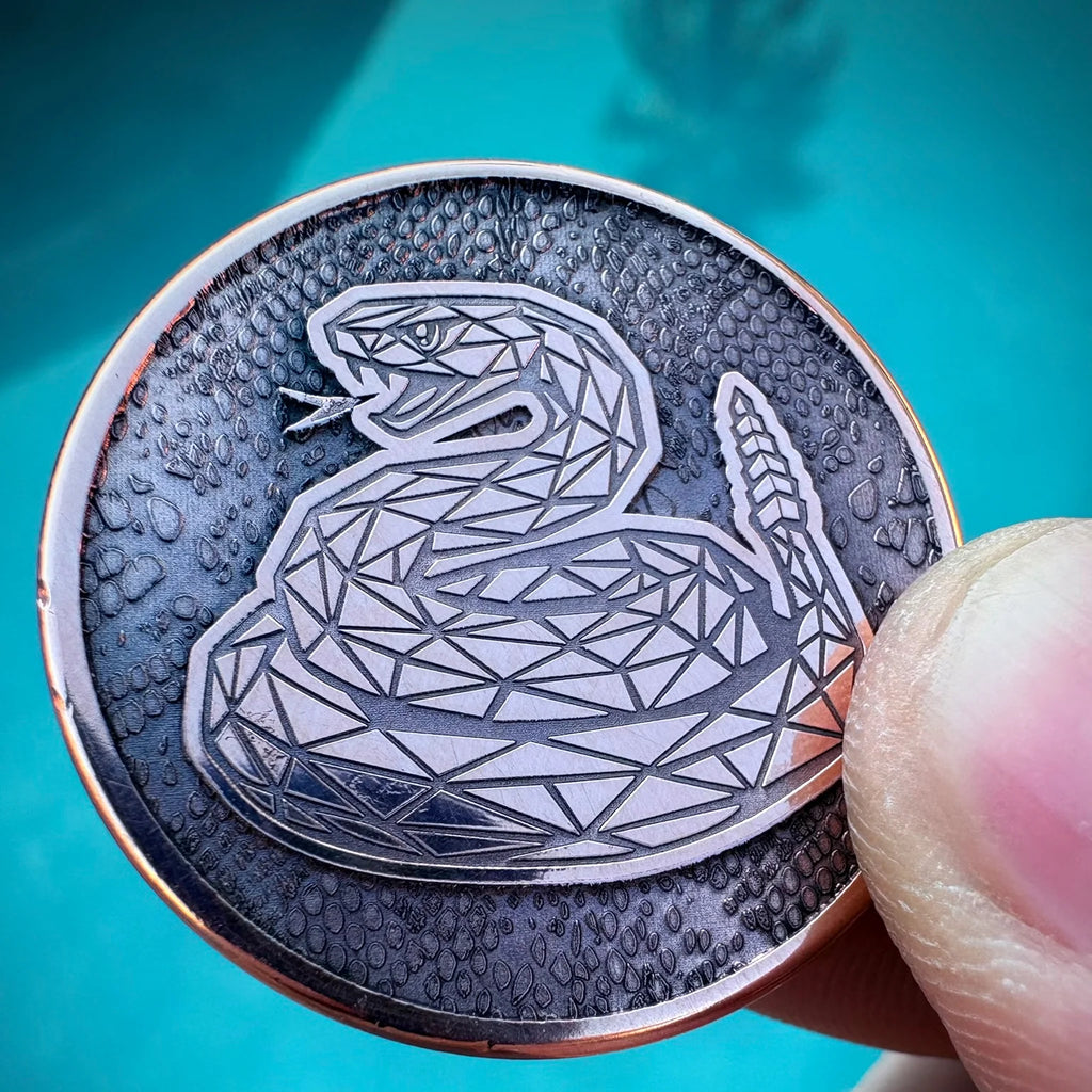 Close-up of a coin with geometric snake design held by a hand against a blue background