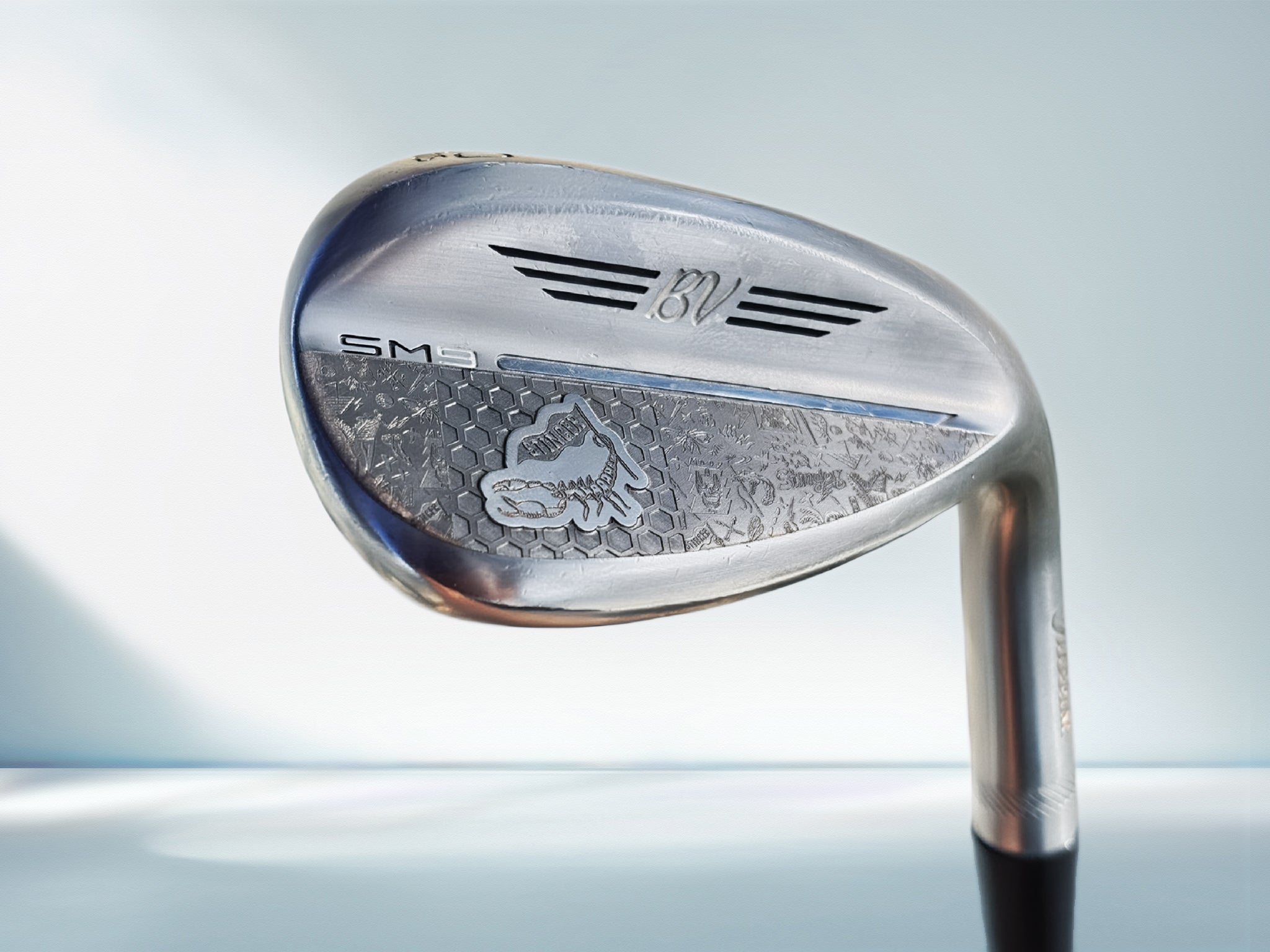 Golf club head with brand logo on a light blue background